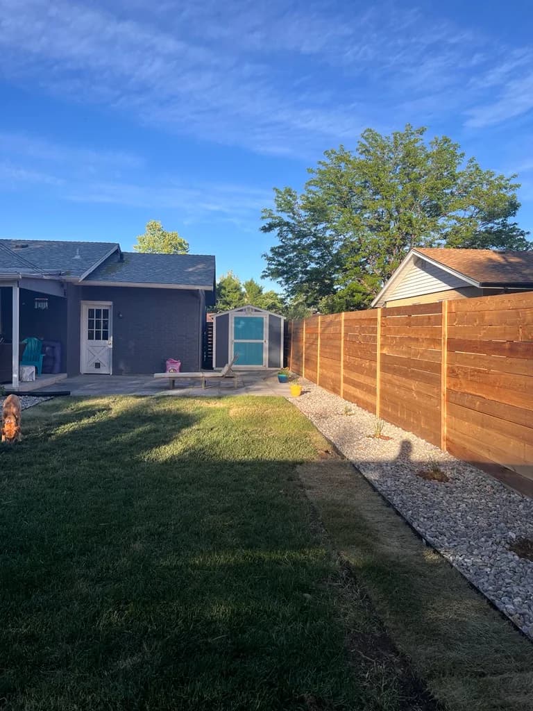 Backyard overview of a completed horizontal cedar privacy fence in Lakewood, Colorado under a blue sky