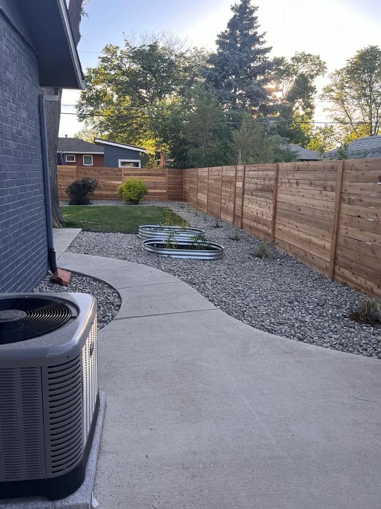 Horizontal cedar privacy fence running along a curved concrete walkway with raised garden beds in Lakewood, Colorado
